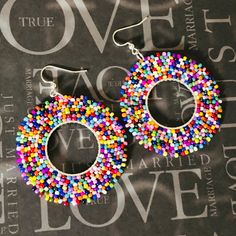 two pairs of multicolored beaded hoop earrings on top of a black background