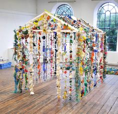 an art installation made out of glass beads and other items in a room with large windows