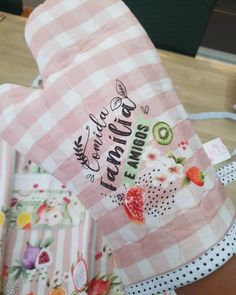 a pink and white checkered paper bag with flowers on the side, sitting on top of a wooden table