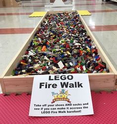 a wooden box filled with legos sitting on top of a red floor next to a sign that says, what sick individual created this