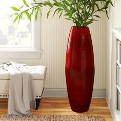 a large red vase sitting on top of a hard wood floor next to a window