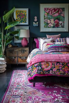 a bedroom decorated in pink and green with lots of artwork on the wall above the bed