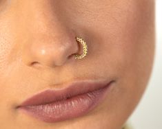 a close up of a woman's nose with a gold nose ring on it