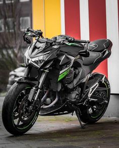 a black and green motorcycle parked in front of a building