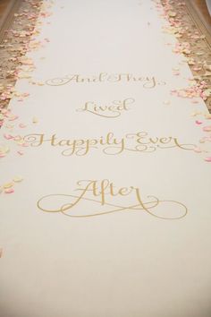 the aisle is decorated with rose petals and gold writing on white paper, which reads happily wed disney wedding ashley & jolie at