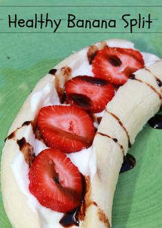 a banana split with strawberries and chocolate sauce on it sitting on a green plate