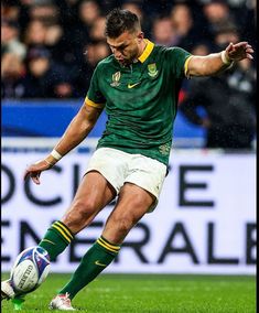 a man kicking a soccer ball on top of a field