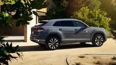 the rear end of a grey volkswagen suv parked in front of a house on a sunny day