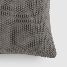 a gray knitted pillow sitting on top of a white wall