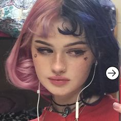 a girl with pink hair and piercings on her ear is holding a cell phone