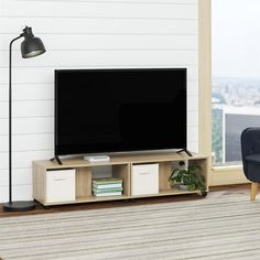 a living room with a large television on top of a wooden stand next to a blue chair