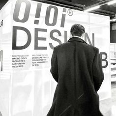 a man in a coat is walking past a sign that reads, ojoi design b