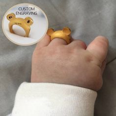 a baby's hand with a gold bear ring on it