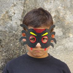 a young boy wearing a black mask with yellow and red eyes