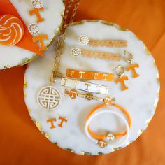 DETAILS: Base Metal with Worn Gold Plating Enamel Material Hinge Closure 2.5" Diameter NCAA Officially Licensed Univ Of Tennessee, Tennessee Logo, Tennessee Fashion, Pearl Cluster Earrings, Orange Details, The Volunteers, Tech Jewelry, Enamel Stud Earrings, Tennessee Vols