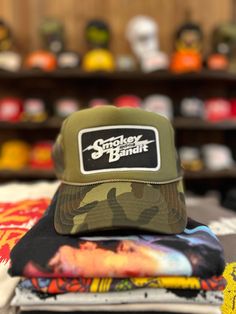 Classic trucker hat featuring a Smokey and the Bandit patch Adjustable snap back One size fits most Curved, moldable bill Trucker Snapback Hat With Patches For Streetwear, Trucker Style Snapback Hat With Patches For Streetwear, Adjustable Green Trucker Hat With Logo Patch, Outdoor Trucker Hat With Patches, Adjustable Trucker Hat With Patches For Outdoor, Outdoor Adjustable Trucker Hat With Patches, Snapback Hats With Patches For Streetwear, Adjustable Baseball Cap With Patches For Streetwear, Adjustable Patches Hat For Streetwear