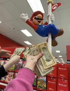 a person handing money to another person in a store with mario and luigi on the pole