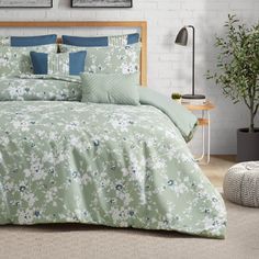 a bed with green and blue comforters in a room next to a potted plant