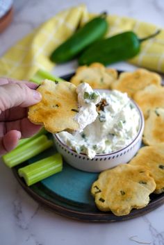 a plate with crackers, celery and dip on it