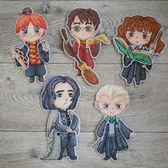 four cross stitch harry potter characters on a wooden floor with one holding a book and the other wearing glasses