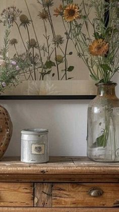 two vases with flowers in them sitting on a wooden table next to a painting