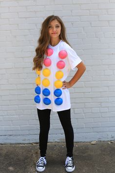 a woman standing in front of a white wall wearing a t - shirt with colorful polka dots on it