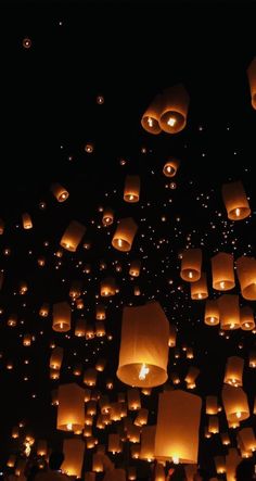 many lanterns are floating in the air at night