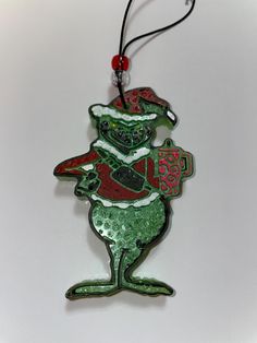 a glass ornament with an image of a green frog wearing a santa hat