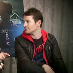 two men sitting next to each other in front of a movie poster