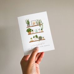 a person holding up a card with plants on it