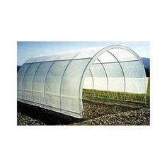 a large white greenhouse in the middle of a field with grass and dirt on the ground