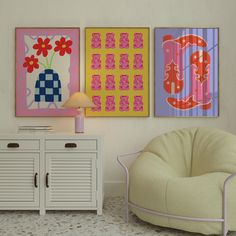 three paintings hang on the wall next to a white cabinet and side table with a lamp