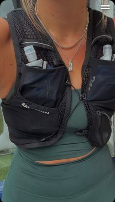 a woman wearing a black vest holding two water bottles