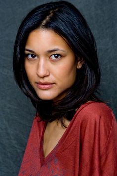 a woman in a red shirt is looking at the camera with an intense look on her face