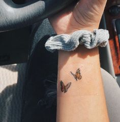 two butterflies on the wrist of a person in a car with their arm wrapped up