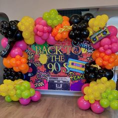 balloons and streamers decorate the backdrop for an 80's themed party