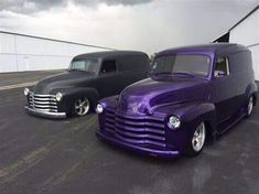 two classic trucks parked next to each other in a parking lot on a cloudy day