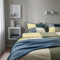 a bed with blue, yellow and green sheets in a bedroom