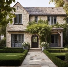 a large house with hedges and trees in front of the entrance to the house is surrounded by greenery