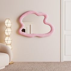 a pink cloud shaped mirror on the wall next to a white chair and lamp in a room