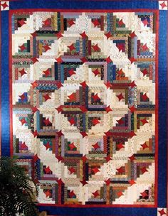 a quilt is hanging on the wall next to a potted plant in front of it