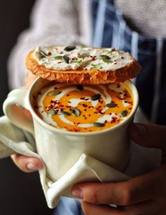 a person holding a cup with food in it and some sort of pastry on top