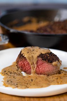 a piece of steak covered in gravy on a plate