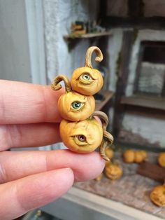 a hand holding two tiny pumpkins with googly eyes