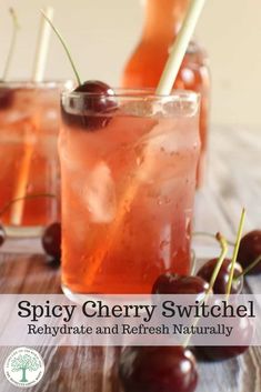 two glasses filled with ice and cherries on top of a wooden table next to each other