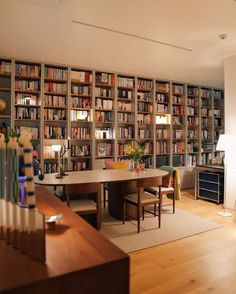 a living room filled with lots of furniture and bookshelves next to a dining table