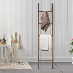 a bathroom with white walls and gray flooring is pictured in this image, there are towels hanging on the rack