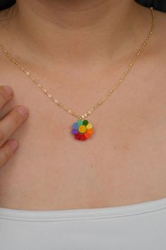 a woman wearing a necklace that has colorful beads on it and is holding her hand in front of her chest