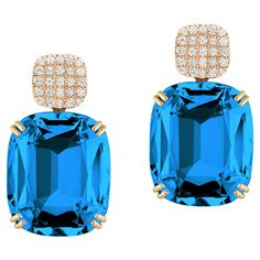 Introducing the stunning London Blue Topaz Cushion & Diamonds Earrings from our popular 'Gossip' Collection. The focal point of these earrings is the mesmerizing London Blue Topaz cushion-cut gemstone. The cushion-cut shape adds a touch of vintage charm, while the vibrant color of the London Blue Topaz exudes a captivating allure. The gemstone is carefully faceted to enhance its brilliance and maximize its natural beauty. O the top of the London Blue Topaz gemstone you can find dazzling diamonds, which add a touch of sparkle and sophistication to the overall design. The diamonds are meticulously set in 18K yellow gold, creating a beautiful contrast against the London Blue Topaz. The craftsmanship of these earrings is impeccable, with attention to detail evident in every aspect. With their Cushion Cut Diamond Earrings, Emerald Cut Diamond Earrings, Cushion Earrings, Stone Dangle Earrings, Blue Topaz Stone, Blue Topaz Earrings, Cushion Cut Diamonds, Topaz Earrings, Unique Diamonds