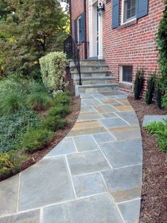 a stone walkway in front of a brick house